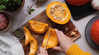 Female cutting pumpkin in slices on cutting board