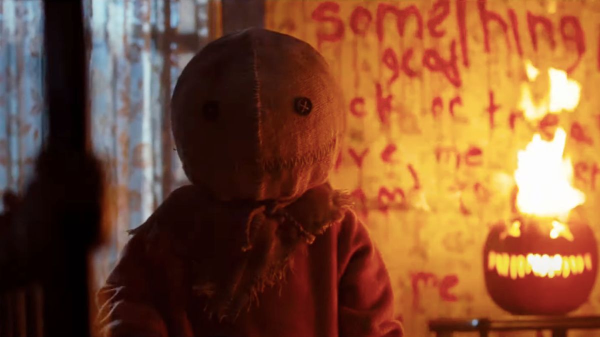 Sam sits next to a flaming pumpkin in Trick &#039;r Treat.