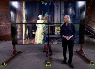 Annie Leibovitz posing with a photo she took of Queen Elizabeth on a large easel