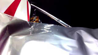 close-up of protective tarp surrounding a spacecraft with a strut and black space also visible