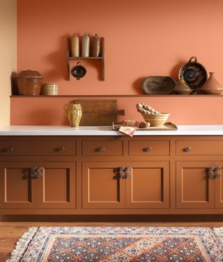 A kitchen painted in a burnt orange color with orange cabinets