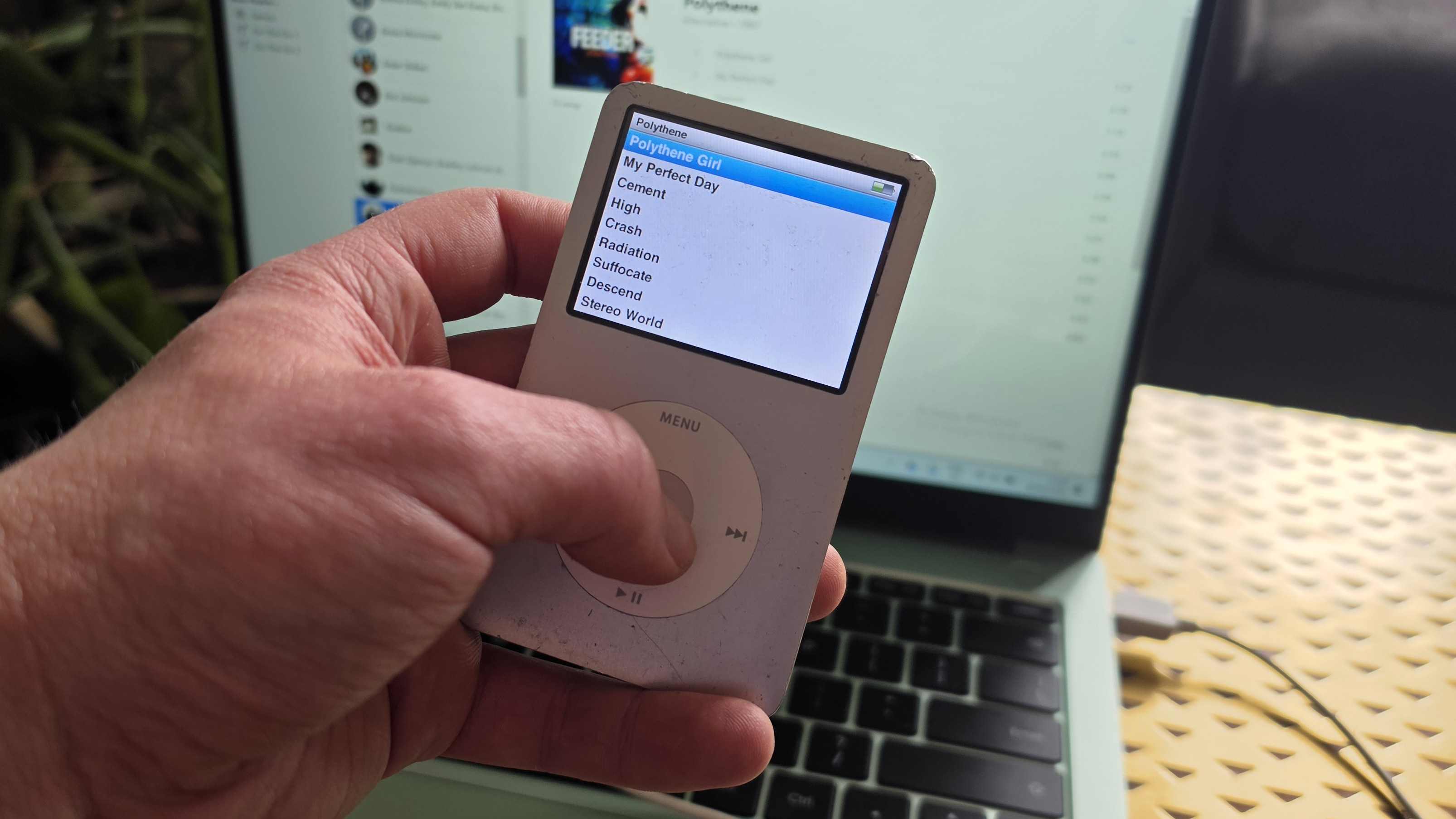 The iPod Classic connected to a green Realme laptop, showing iTunes.