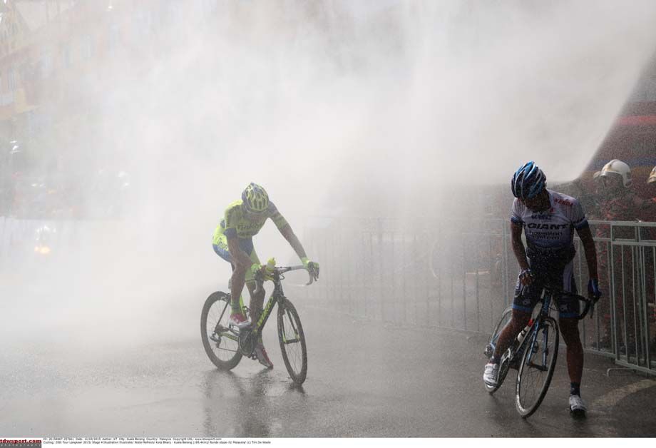 Riders enjoy the cooling spray of water at the end of a Tour de Langkawi stage