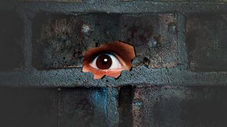 Eye looking through the hole on cracked wall. Spy peeking through hole in brick wall. Spy concept.