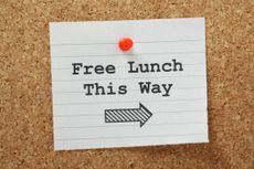 Notepaper with "Free Lunch This Way" written on it pinned to a corkboard