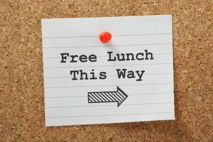 Notepaper with "Free Lunch This Way" written on it pinned to a corkboard