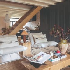 An open-plan living room with a panelled black-painted wall and wooden coffee table and side table