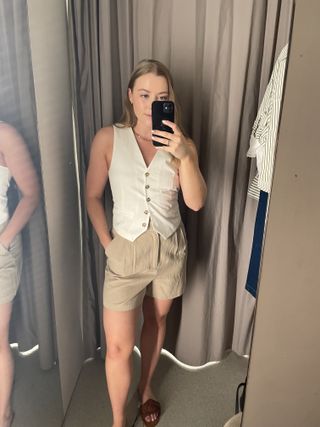 Woman wears white vest and beige linen shorts