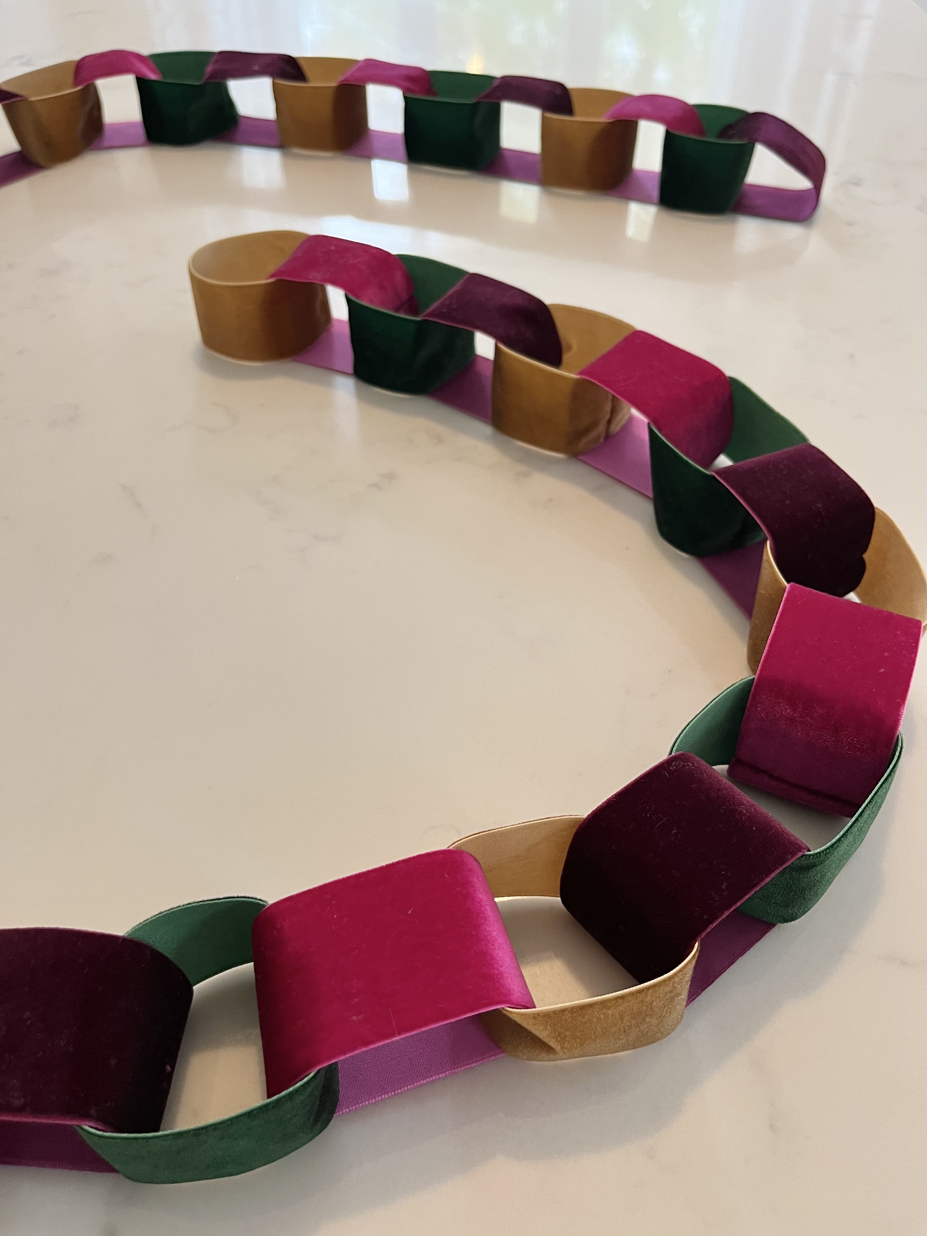 A chain made out of colorful velvet ribbon draped on a table