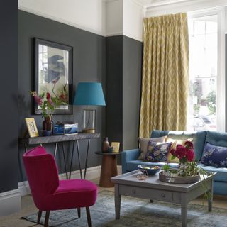 dark grey living room with fushia armchair, turquoise table lamp and yellow curtains