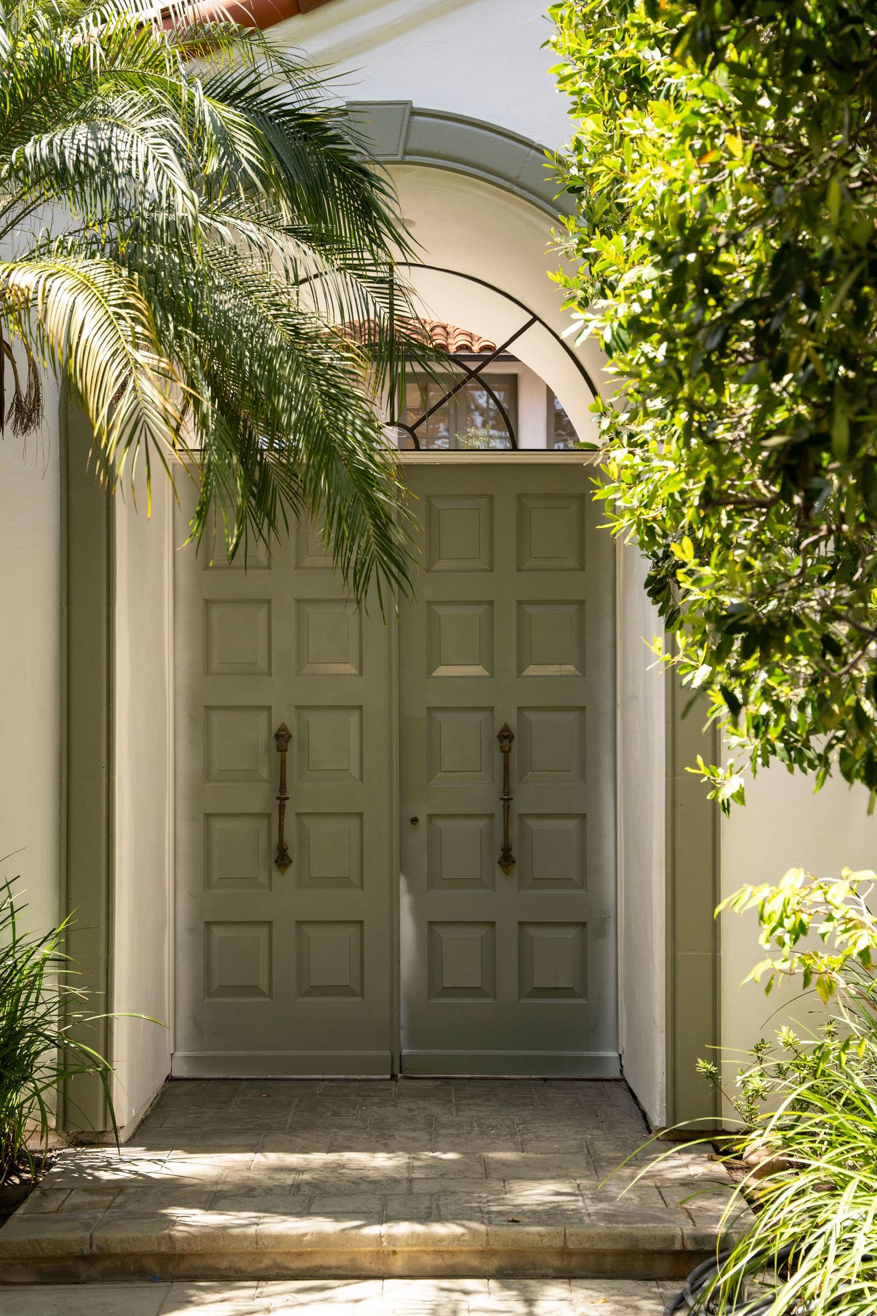 An outdoor space with an arch and a green entrance door