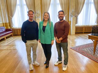 Phil MacHugh and Martin Compston stand in the Norwegian parliament building in Oslo, with Norway's youngest MP, Maren Grøthe, standing between them