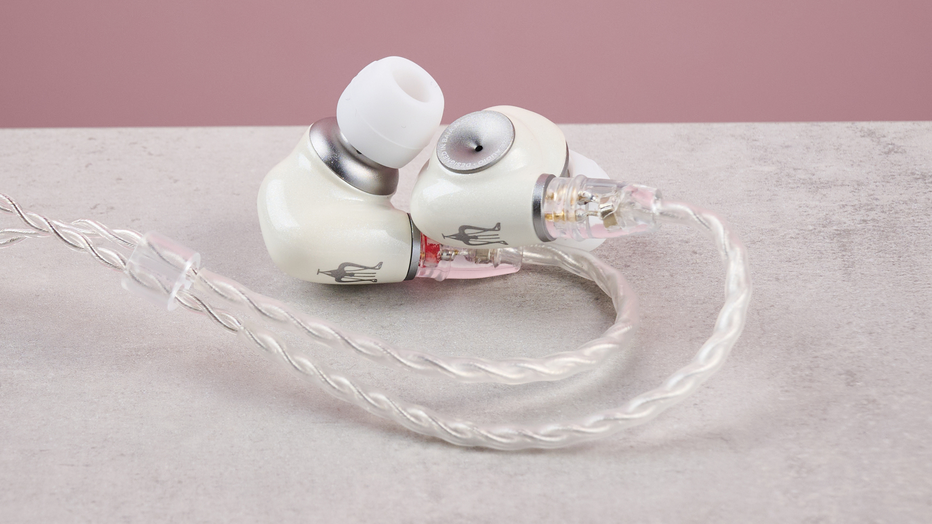 Meze Alba IEMs on a table against a pink background