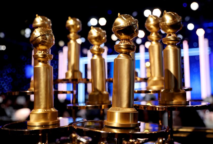 A collection of Golden Globes trophies displayed on a table in front of a stage