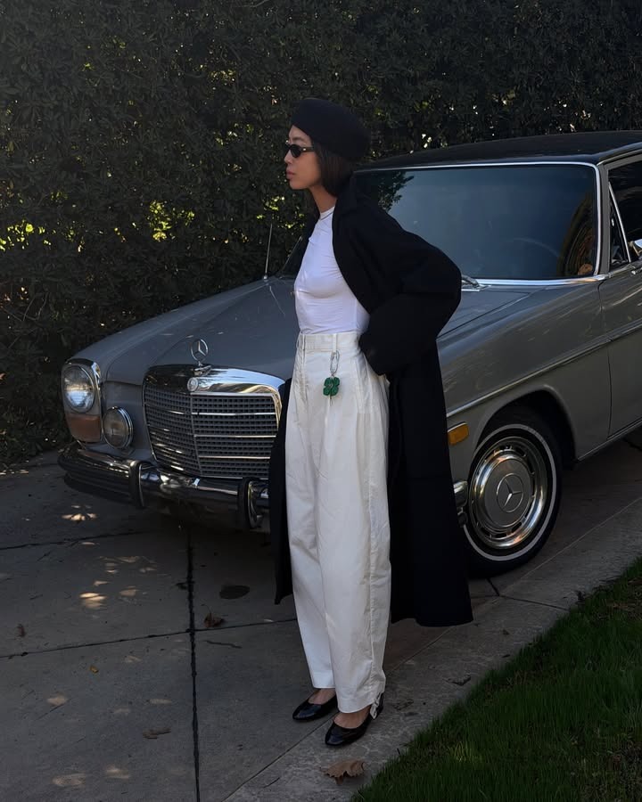 Woman wears black hat, white T-shirt, cream trousers, black trousers