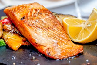 A salmon fillet next to a wedge of lemon