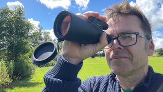 Man using the Python 12x52 Range Master Ultra HD Monocular in a park