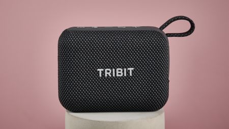 Tribit PocketGo on stand, against pink background