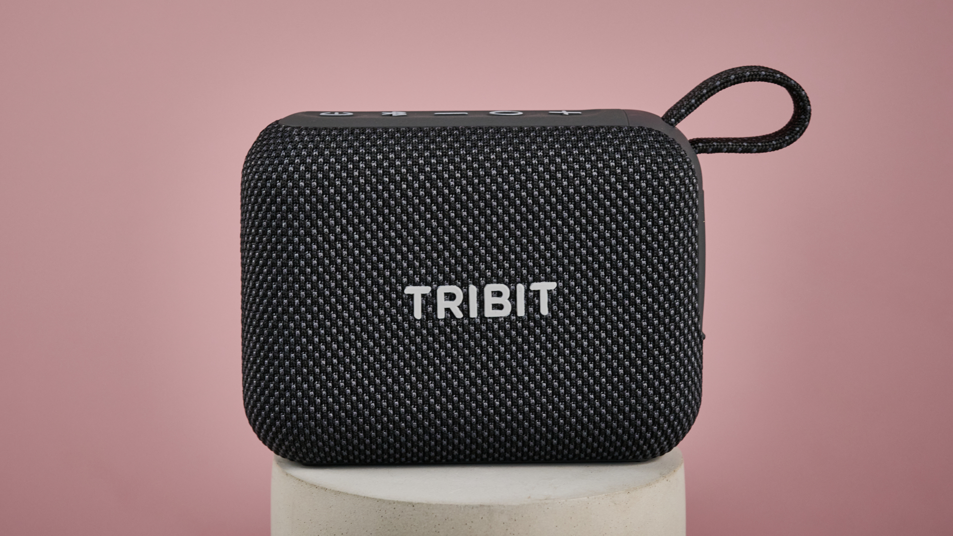 Tribit PocketGo on stand, against pink background