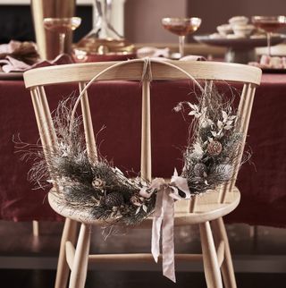 wooden hoop christmas wreath hanging on back of wooden chair