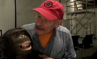 Man wearing cap holding a monkey sculpture