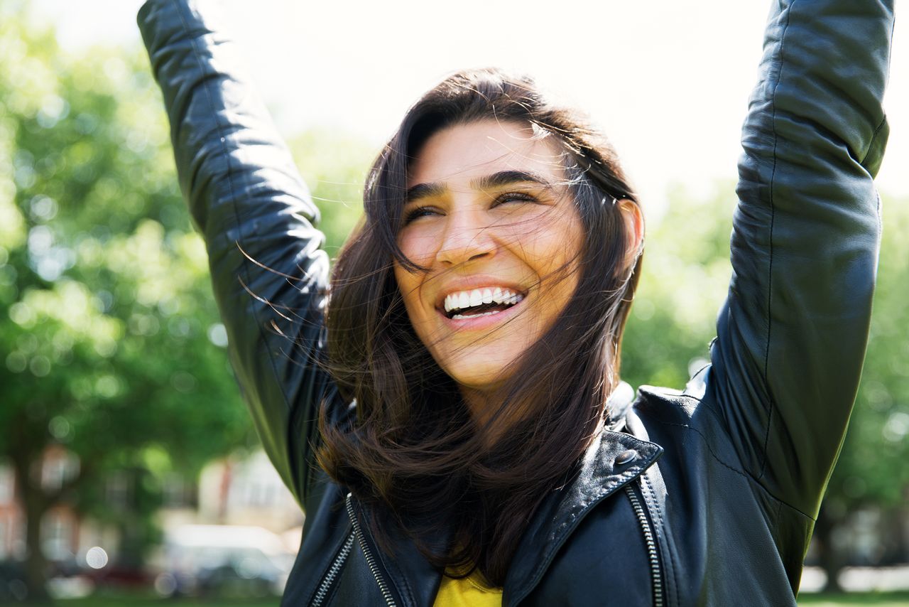 woman smiles with her hands in the air