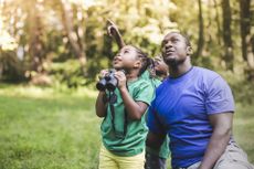 A father with his children bird watching outdoors.