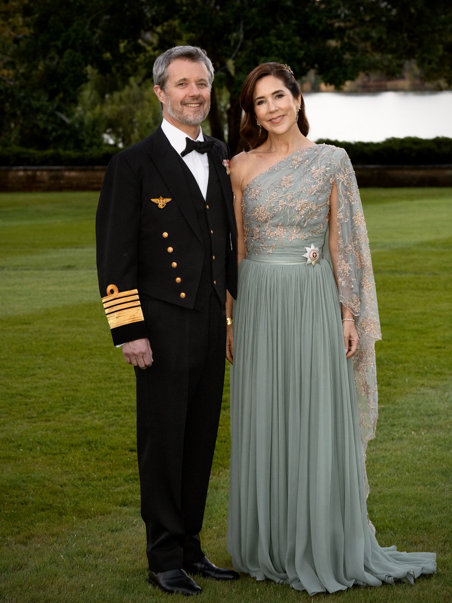 Queen Mary wearing a mint green gown posing next to King Frederik