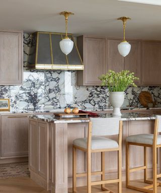 kitchen with marble backsplash and pale wood cabinets and island