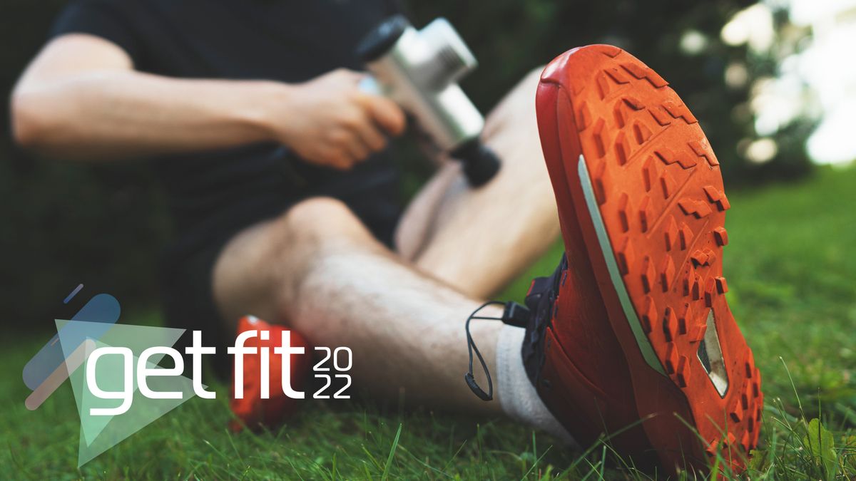 Man sitting outside after a run using massage gun on his leg