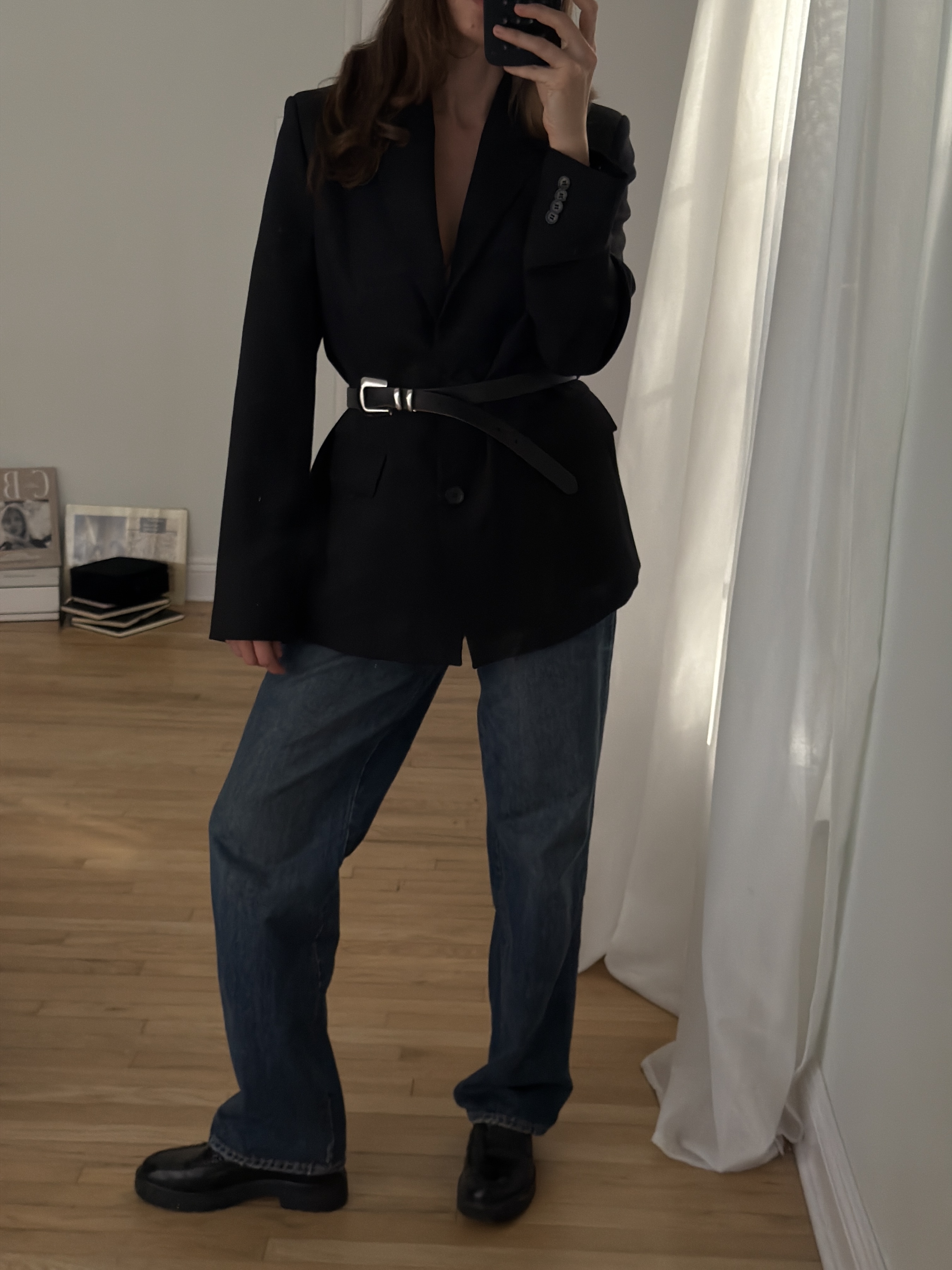 Kathryn Zahorak posing in mirror wearing black blazer, belt, baggy jeans, black boots