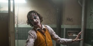 The Joker (Joaquin Phoenix) dances in a grimy bathroom.