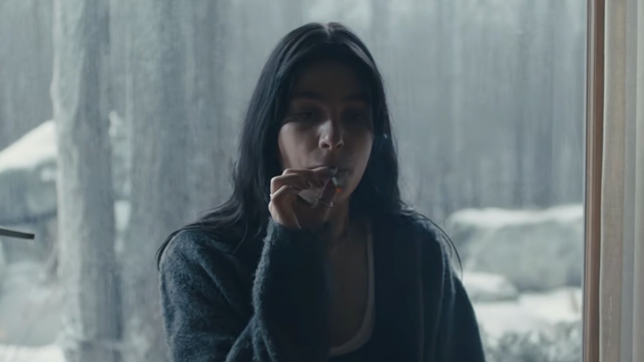 Rachel taking a hit off of a joint while sitting in front of a window in Soemthing Very Bad Is Going to Happen