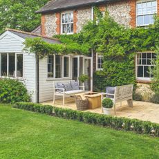 A back garden with a green lawn and garden furniture set 