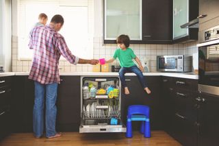 A father and children stacking dishes in a dishwasher