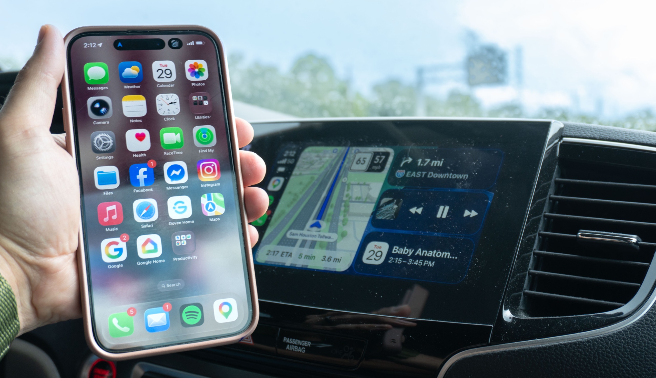 A phone in hand in front of an infotainment screen showing how the Ottocast OttoSafe Cam upgrades your car to wireless CarPlay