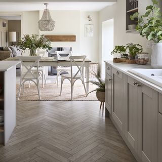 Grey Shaker kitchen with white worktops and a farmhouse table in dining area.