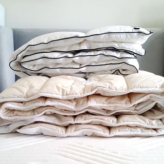 A selection of folded duvets piled on a mattress