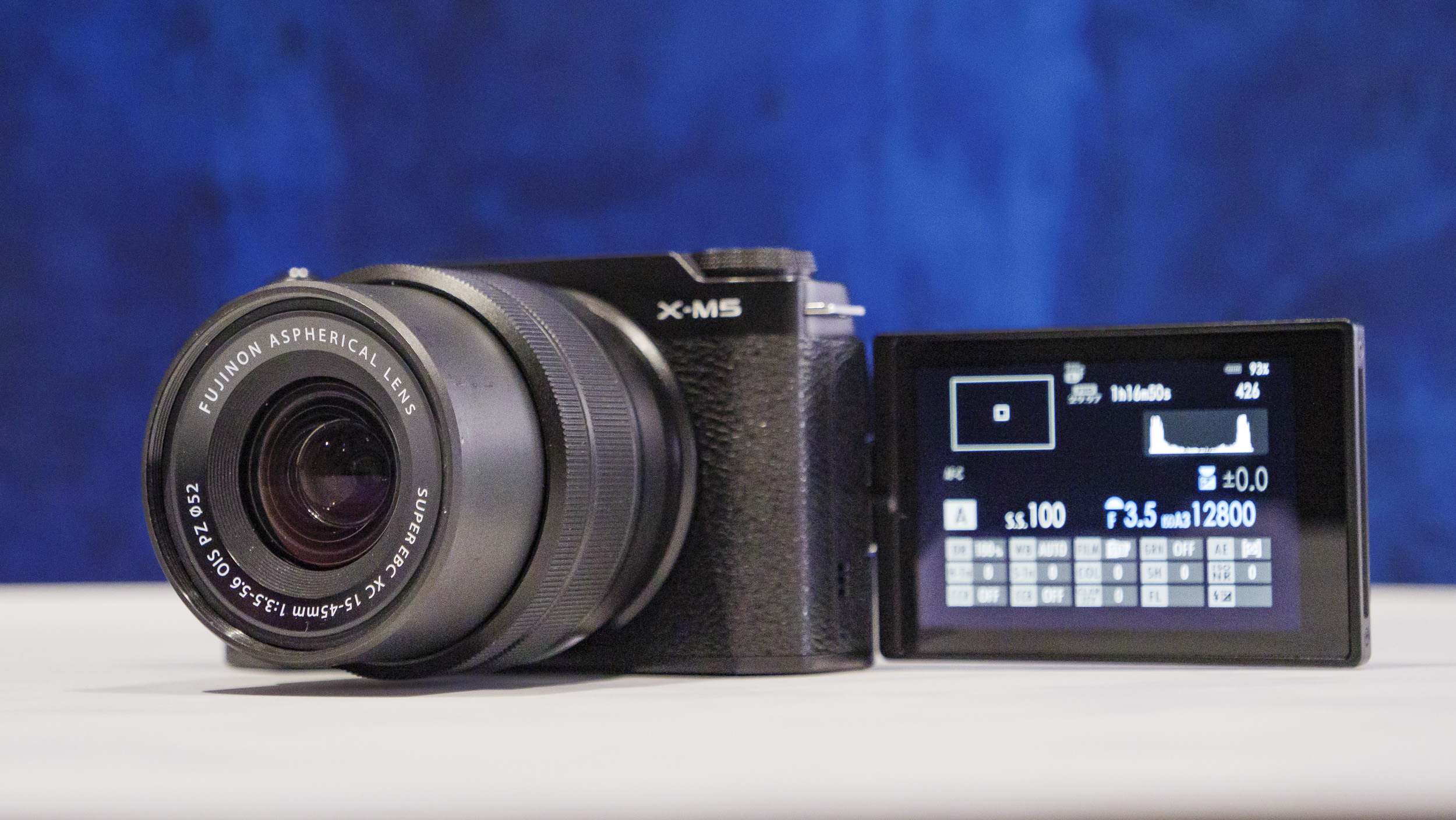 Fujifilm X-M5 camera on a marble surface with rich blue background with flip screen out