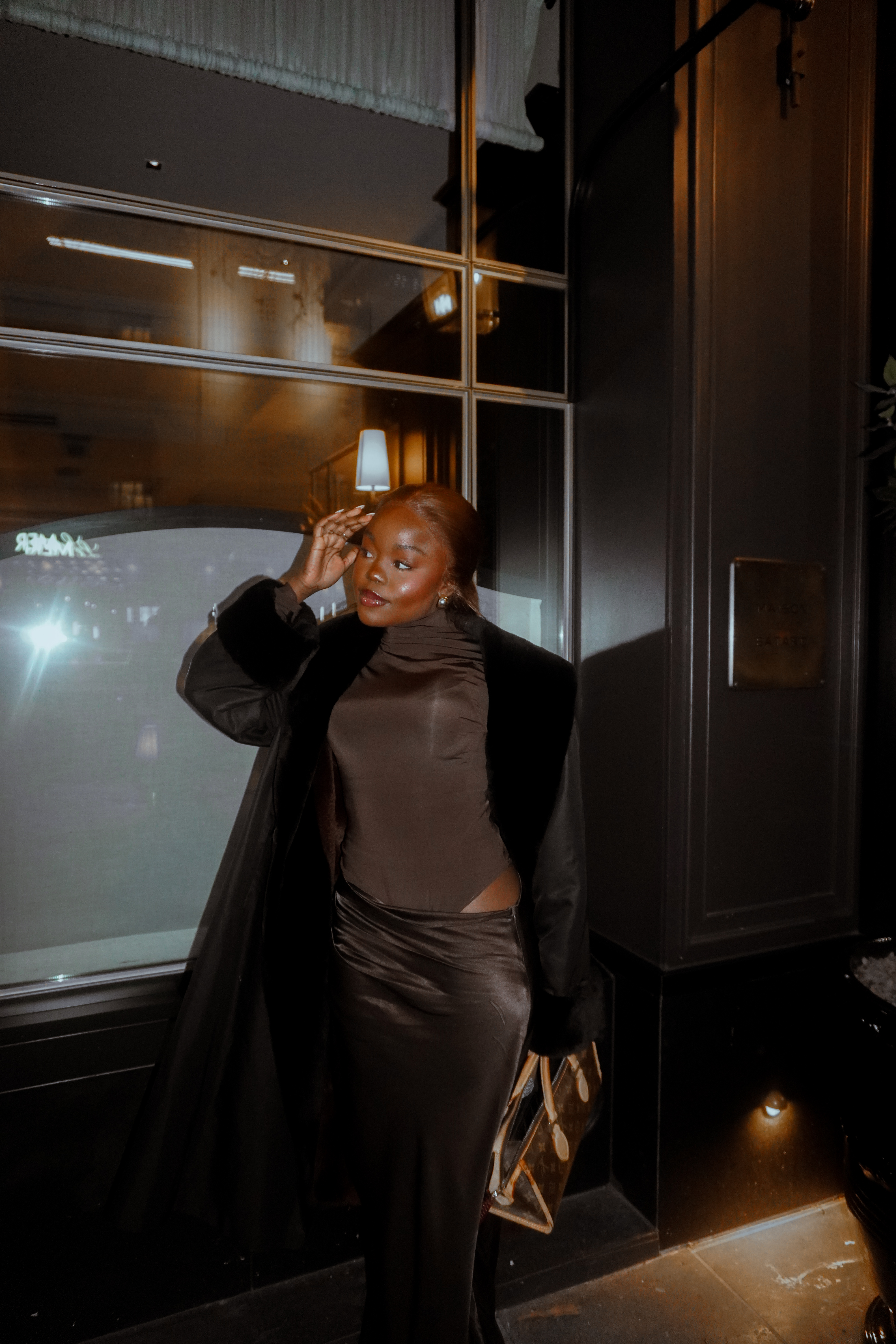 Tatenda wears a fur coat and a brown maxi dress with a Louis Vuitton bag.