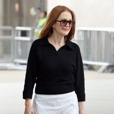 Julianne Moore wearing a black top, white pants, and sunglasses in London