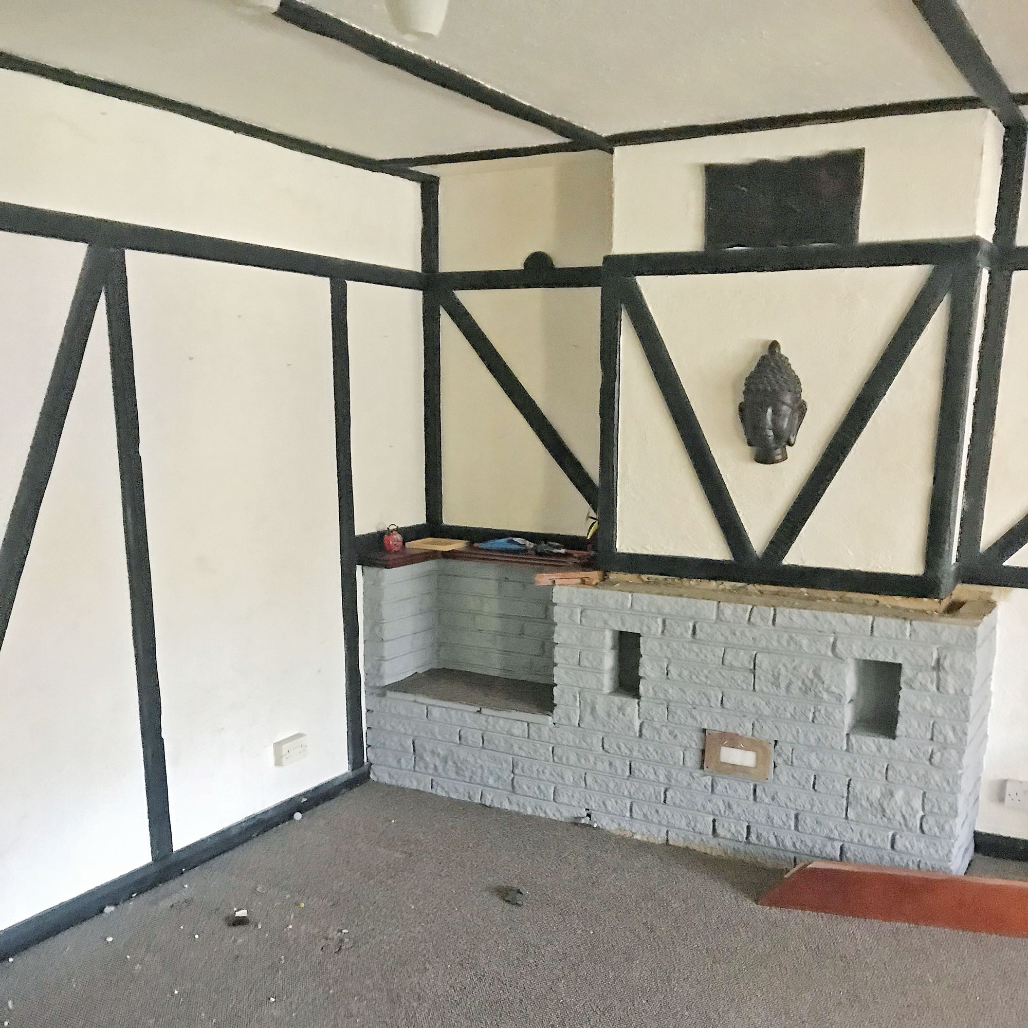 Before shot of a living room with a fireplace and beams on the wall