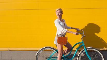 Woman on a bike cycling against a yellow wall