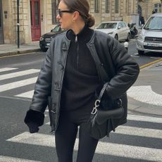 Influencer @annelauremais wears black leggings with knee-high black boots and a black leather jacket.