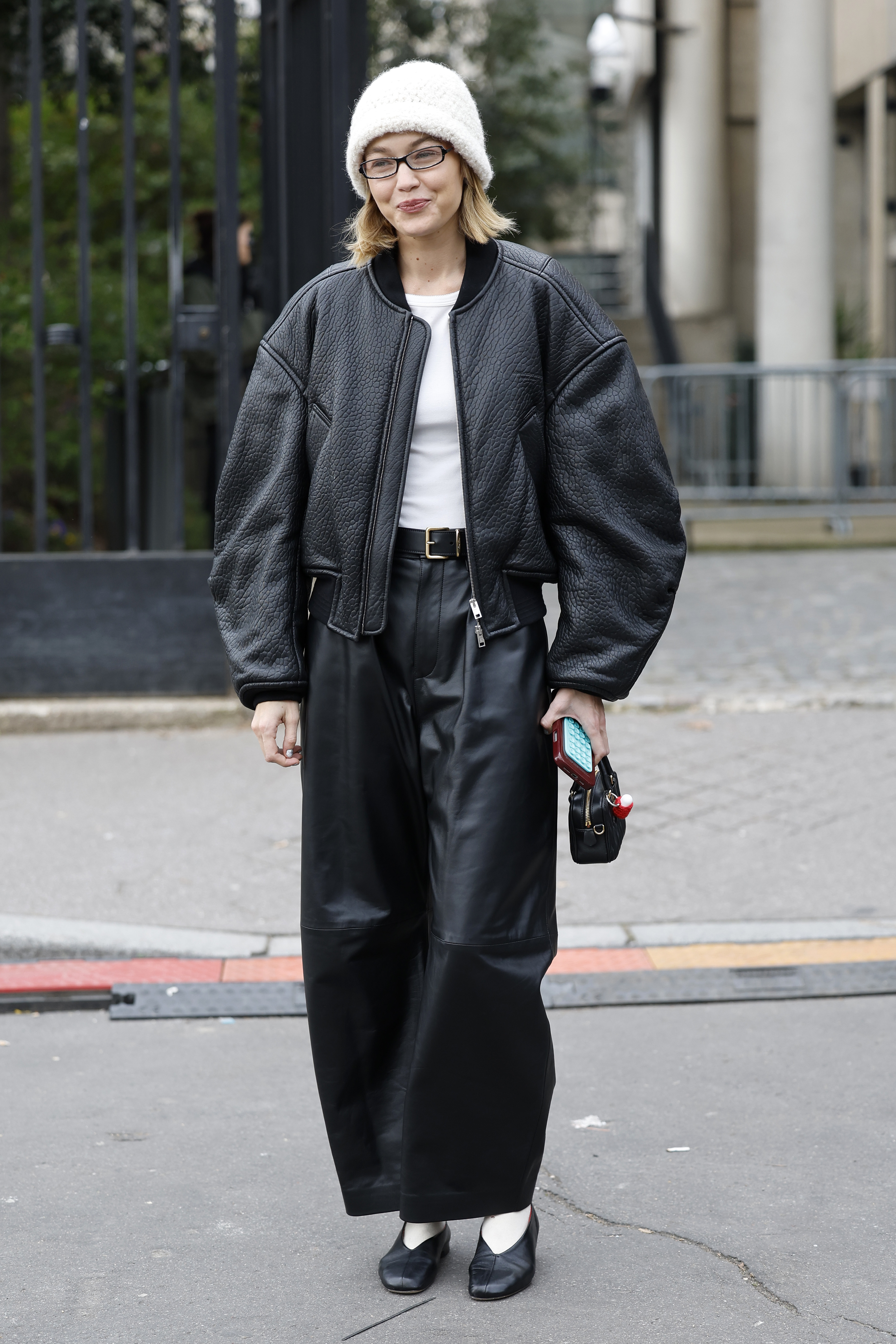 Gigi Hadid wearing a white t-shirt, a bomber jacket, leather pants, and high-vamp flats