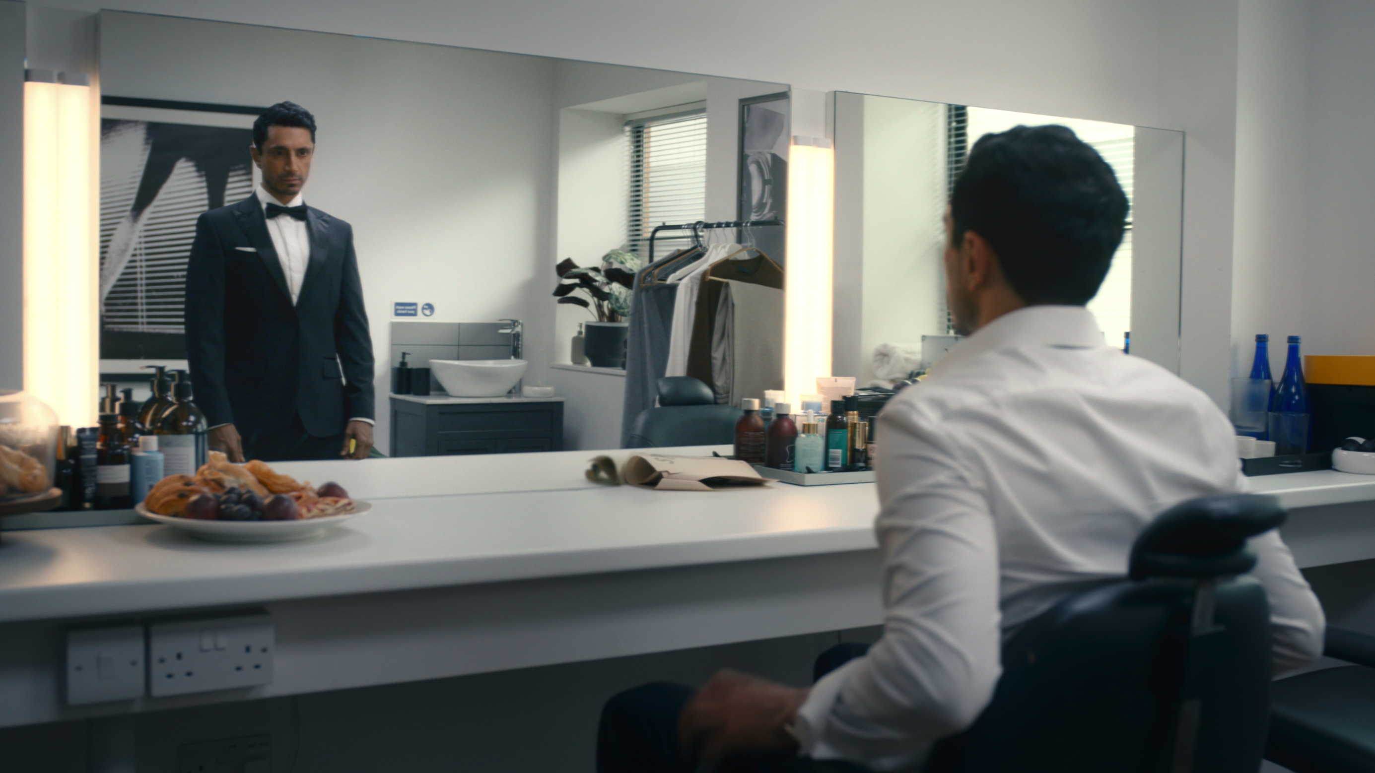 Shah Latif (Riz Ahmed) looks at his own reflection dressed in a James Bond tuxedo in a mirror in a scene from Prime Video's &amp;quot;Bait&amp;quot;