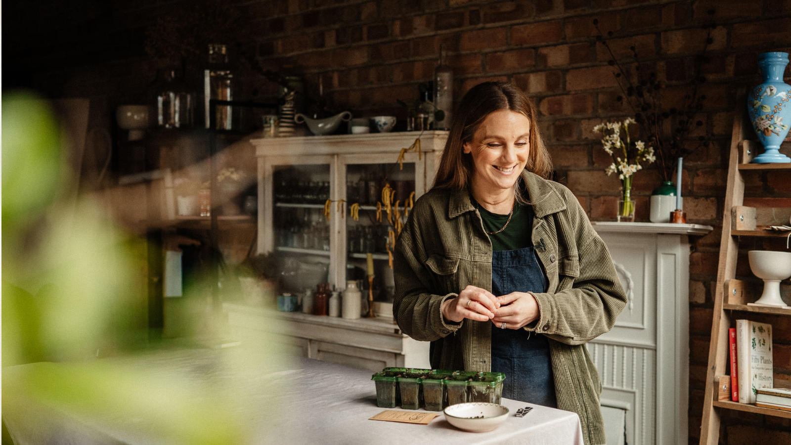 woman in potting shed plating seeds into a seed tray