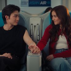 kitty covery song and min jo hold hands on a flight together before it takes off in a still from the xo kitty season 3 finale