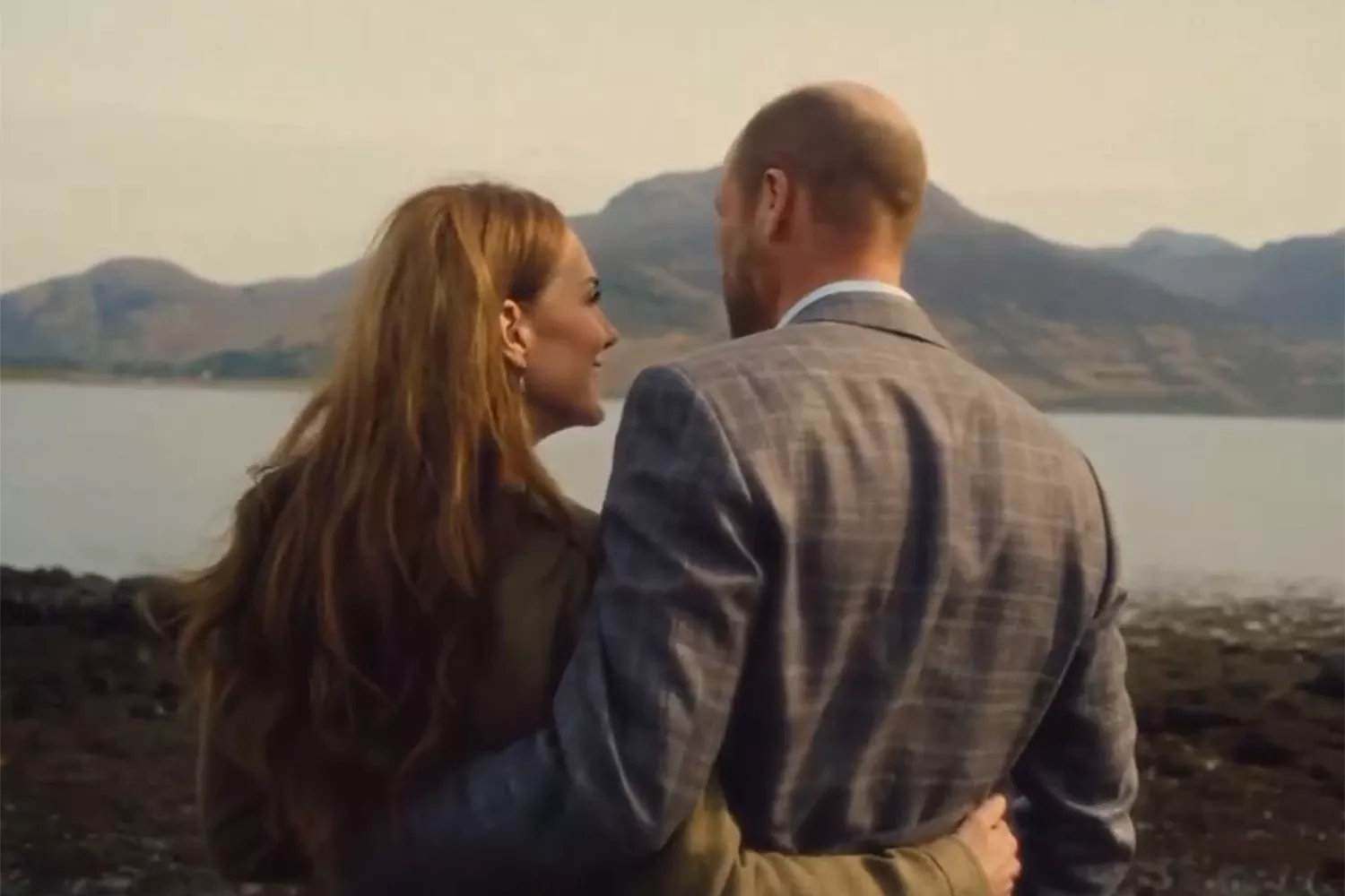 Prince William and Kate with their arms around each other in front of a lake
