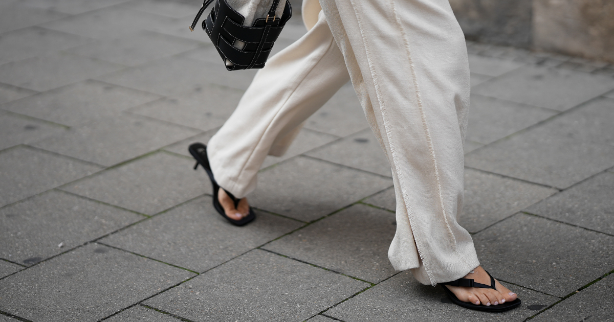 Toe Hair Anouk Delphine is seen wearing a beige linen like the palazzo pants with selvedge detail; a black bucket leather hand bag with white stitches